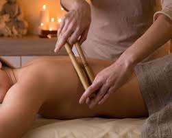 woman giving a warm bamboo massage to another woman on a wellness retreat in Bali with candles in the background