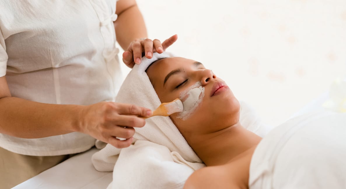 Woman getting a facial mask applied by spa therapist on a Bali wellness retreat