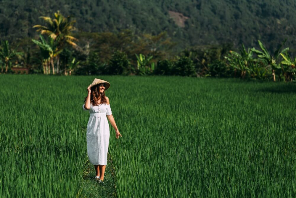 Woman walking through lush green rice paddies during a guided tour in Ubud, Bali.
