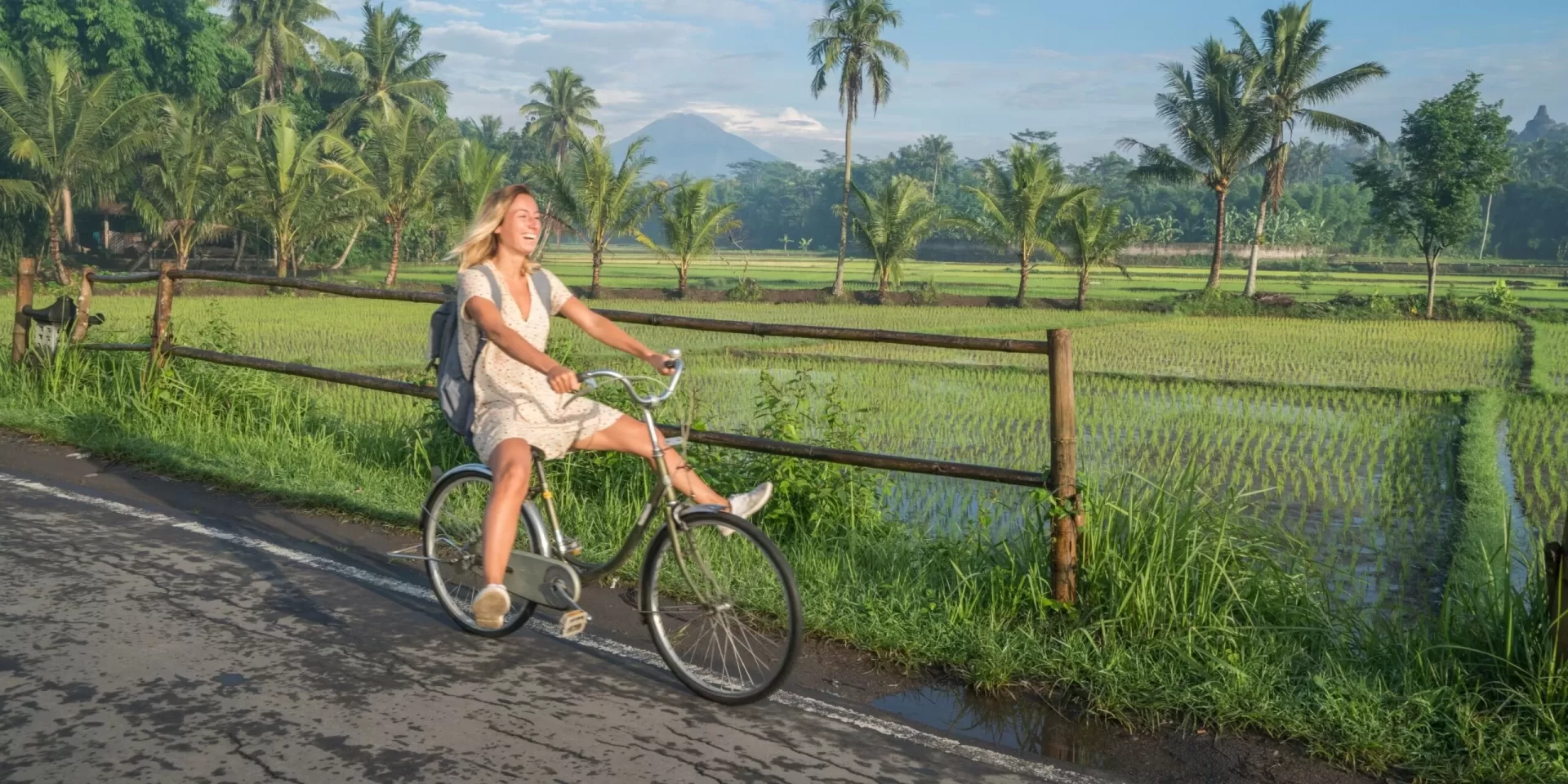 a woman riding a bicycle though bali rice paddies on a bali wellness retreat for women